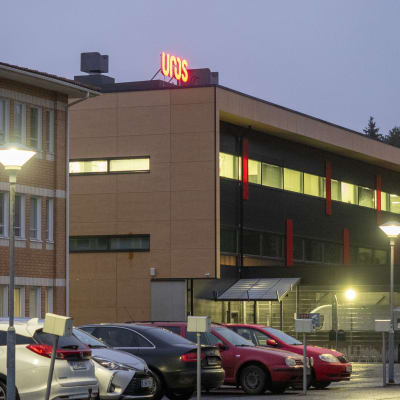 Uros Oy:n  valomainos kerrostalon katolla. Edessä pysäköityjä autoja.