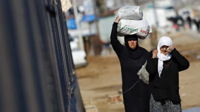Syriska kvinnor bär på mat vid den Turkiska gränsen.