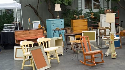 Möbler från olika tidsepoker på en loppmarknad utomhus.