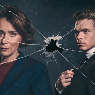 Keeley Hawer ja Richard Madden Bodyguard-sarjan markkinointikuvassa. Henkilöiden edessä luodin rikkoma ikkuna.