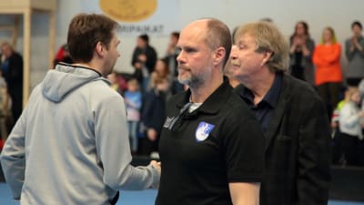 Chefstränaren Sebastian Freudenthal och lagledaren Stig Söderholm gratuleras av Karhut efter ligakvalet.