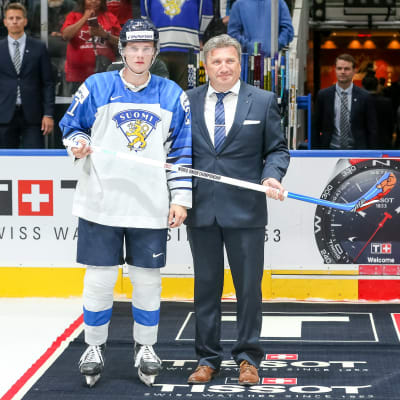 Aleksi Heimosalmi och en IIHF-representant poserar med priset för matchens bästa spelare.