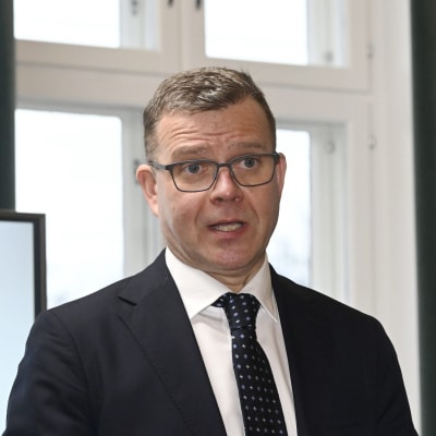 Petteri Orpo framför Samlingspartiets kampanjsloganer.