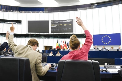 Två Europaparlamentariker sträcker upp sina händer under en omröstning i parlamentet