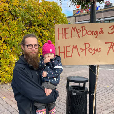 Man med dotter och plakat på demonstration.