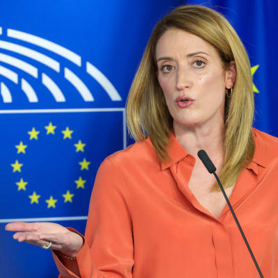Roberta Metsola taustallaan EU:n lipun kuva.