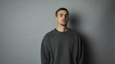 Henrik Suhonen harmaassa collegepaidassa harmaata taustaa vasten.