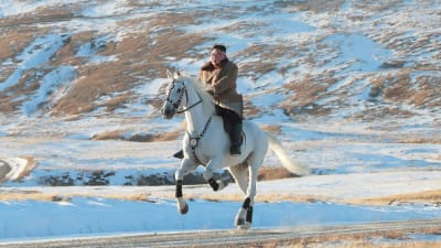 Kim Jong-un rider på en häst som rusar fram över ett snöbeklätt landskap. 