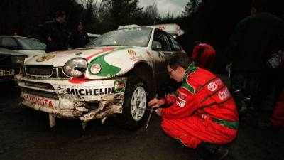 Timo Rautiainen och Marcus Grönholm byter däck på den smått demolerade rallybilen i VM-rallyt 1998 i Wales.