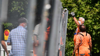 Arbetare i orange overaller bygger ett stängsel