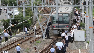 Passagerare går längs ett järnvägsspår i Osaka efter att trafiken stoppats på grund av skalvet. 