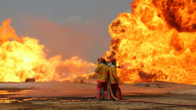 Brandmän försöker släcka brand på oljefält i Kirkuk som IS-krigare tänt på.