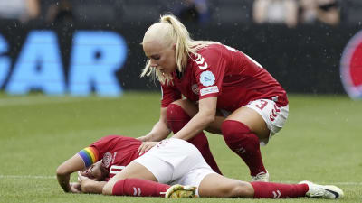 Spelare i rött ligger ner på gräset.