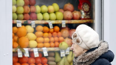 En kvinna går förbi en fruktbutik i Moskva.