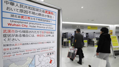 Passagerare går förbi en skylt på Narita internationella flygplats i Japan. 