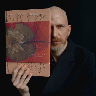 Konstnären och designern Martin Bergström med boken "Flora poetica" i handen.