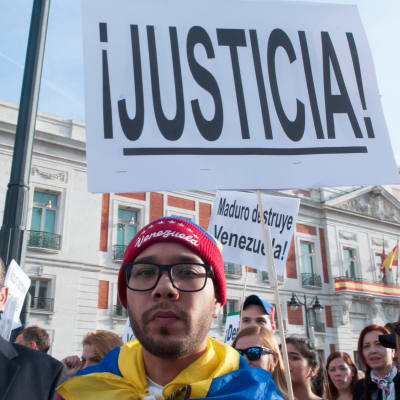 Demonstranter utanför Venezuelas konsulat i Madrid den 30 april. En demonstrant håller en skylt där det står Justicia - rättvisa. 