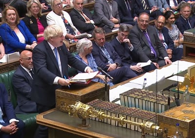 Boris Johnson talar i brittiska underhuset. Omkring honom sitter andra parlamentsledamöter och på bordet framför ligger en spira och böcker.