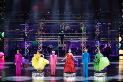 Färggrannt klädda kvinnor och män på scenen.