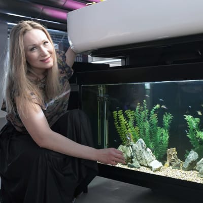 Toimittaja Helena Lappeteläinen on vesi-ja kasviviljelyä yhdistävän aquaponicsjärjestelmän vierellä.