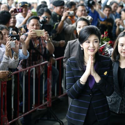 Jingluck Shinawatra hälsar på sina anhängare då hon anländer till domstolen i Bangkok. Hon riskerar upp till tio års fängelse