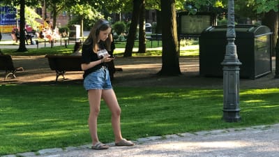 Ung flicka lyssnar på Röster ur pestens år i Gamla kyrkoparken.