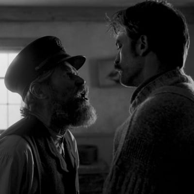 Thomas (Willem Dafoe) och Ephraim (Robert Pattinson) står mittemot varandra och ser arga ut.