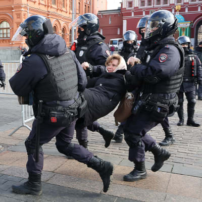 Rysk kravallpolis bär bort en kvinna som demonstrerat mot Rysslands krig mot Ukraina i Moskva den 13 mars 2022.