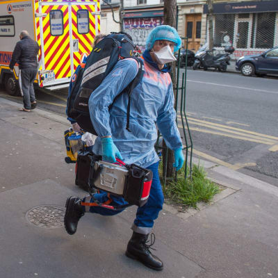 Ambulanspersonal ska vårda en patient i Paris som uppvisat symptom på covid-19.
