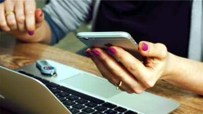 Flicka använder smarttelefon och dator.
