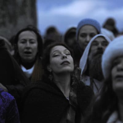 Kvinnor som firar vintersolståndet vid Stonehenge i England. Deras ögon är slutna.