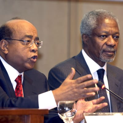 Mo Ibrahim puhuu mikrofoniin. Kofi Annan istuu vieressä.