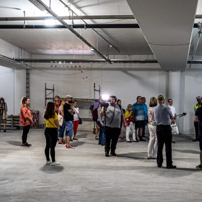grupp människor som går en rundvandring och tittar på underjordiska parkering som byggs i åbo centrum