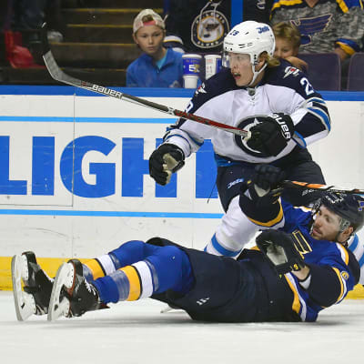 Patrik Laine ser på pucken och Joel Edmundson ligger på isen.