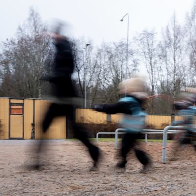 Suddig bild på barn och vuxna som dansar genom en lekpark. 