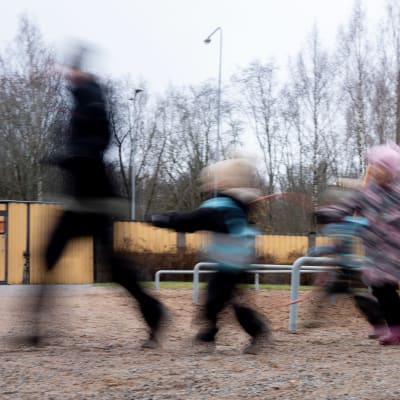 Suddig bild på barn och vuxna som dansar genom en lekpark. 