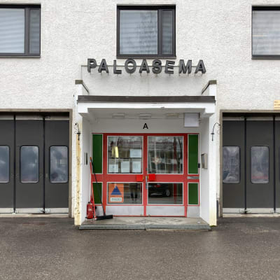 Rovaniemen paloaseman punainen pääovi, yllä teksti paloasema. Sivuilla autotallien ruskeat nosto-ovet.