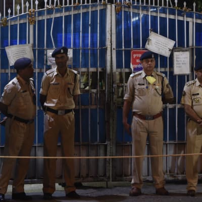 Fem vakter utanför ett stängsel i New Delhi, Indien.