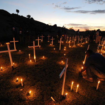 Levande ljus och vitmålade kors i mörkret i en sluttning. 