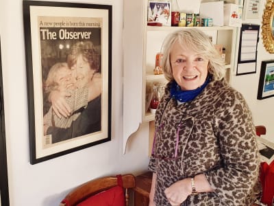 Jane Morrice i sitt kök. På planschen tidningen The Observers förstasida 22 maj 1998, den dag nordirländarna röstade för att godkänna långfredagsavtalet. På tidningsbilden ser man en lycklig Jane krama om en annan kvinna.