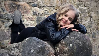 Emmi ligger på mage på några stenbumlingar