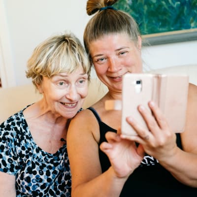 Vanhempi ja nuorempi nainen ottavat yhdessä selfietä.