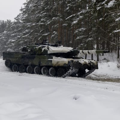 Panssarivaunu ajamassa lumisessa metsässä.