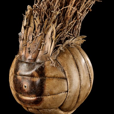 Volleyboll som är ljusbrun och sliten och har ett målat brunt ansikte och hår bestående av torkade växter.