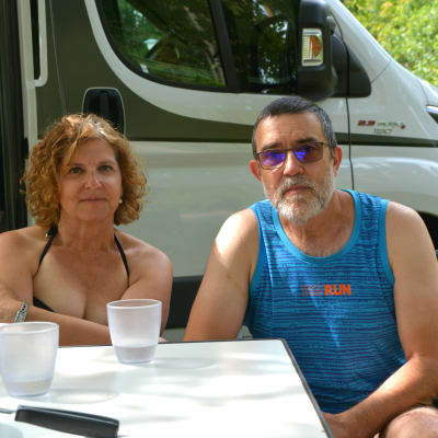 En kvinna och en man sitter vid ett bord framför en husvagn.