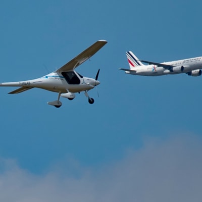 Pieni heiveröinen sähkölentokone lentää etualalla. Taustalla Air Francen Airbus.