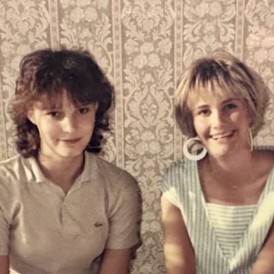 Valokuvassa Leena Harmas ja Susanna Sirén-Valanta istuvat vierekkäin ja katsovat kameraan. Muodista ja meikistä näkee, että kuva on 1980-luvulta.