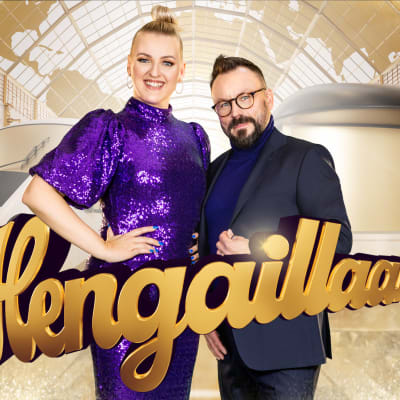 Jenni Poikelus ja Riku Rantala hymyilevät kameralle, takanaan juna ja asema.