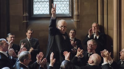 Winston Churchill (Gary Oldman) går segertecknet omringad av en massa människor.