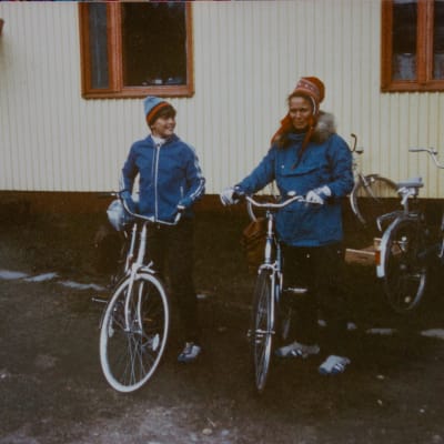 Kuvassa on Priitta Pöyhtäri-Tröen 13-vuotiaana äitinsä kanssa. Molemmilla on siniset takit ja pyörät.
